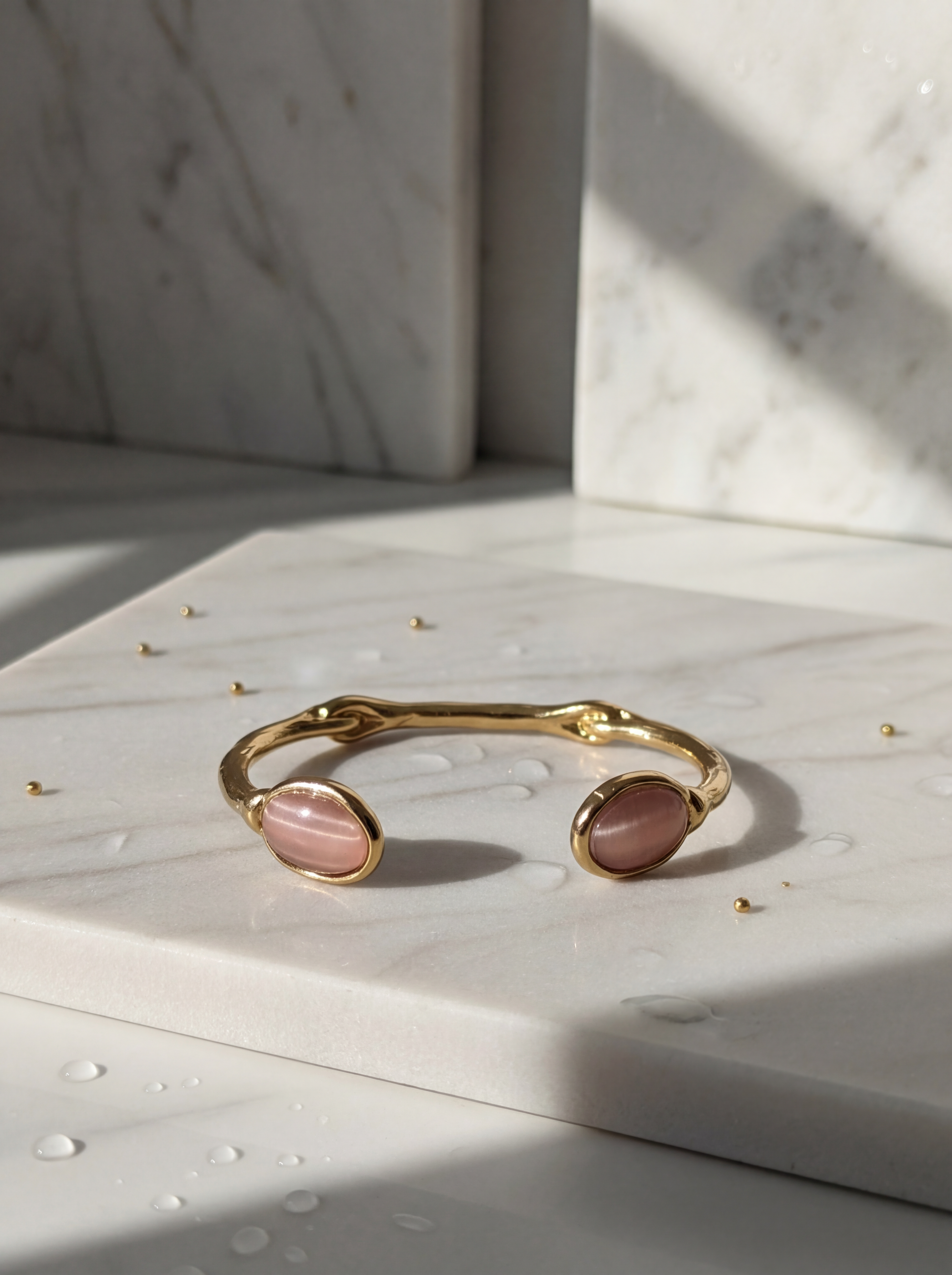 Gold bracelet with pink stones on a marble surface
