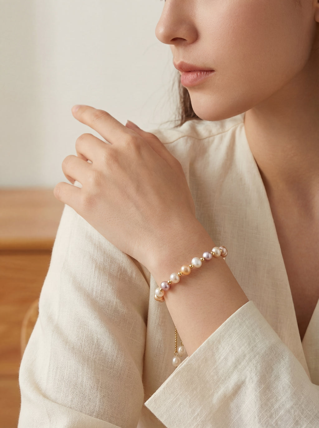 Woman wearing a pearl bracelet on a neutral background