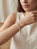 Woman wearing a pearl bracelet on a neutral background