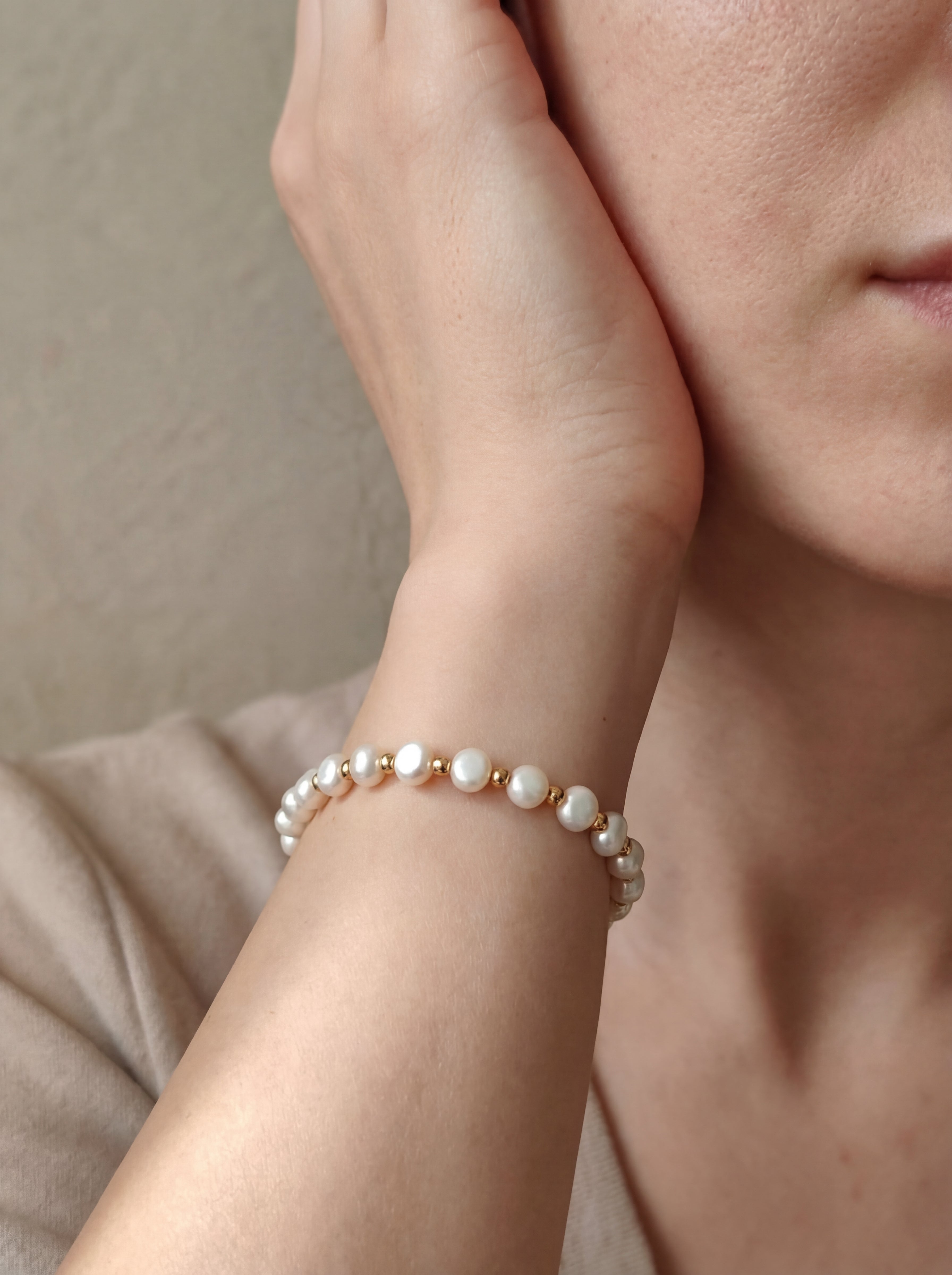 Pearl bracelet on a wrist with a neutral background