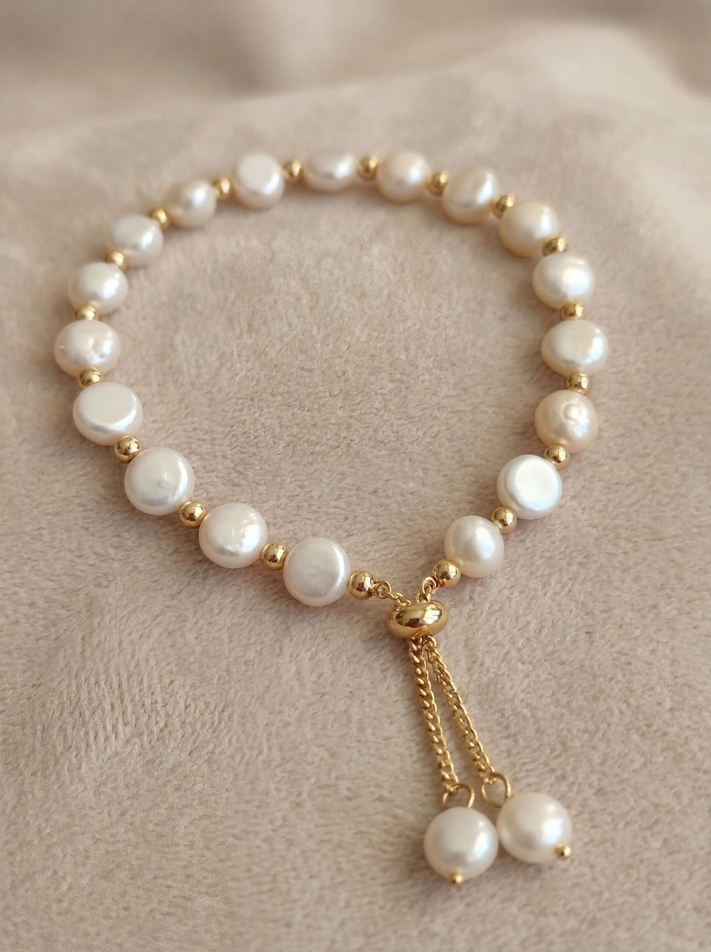 Pearl bracelet with gold accents on a beige fabric background