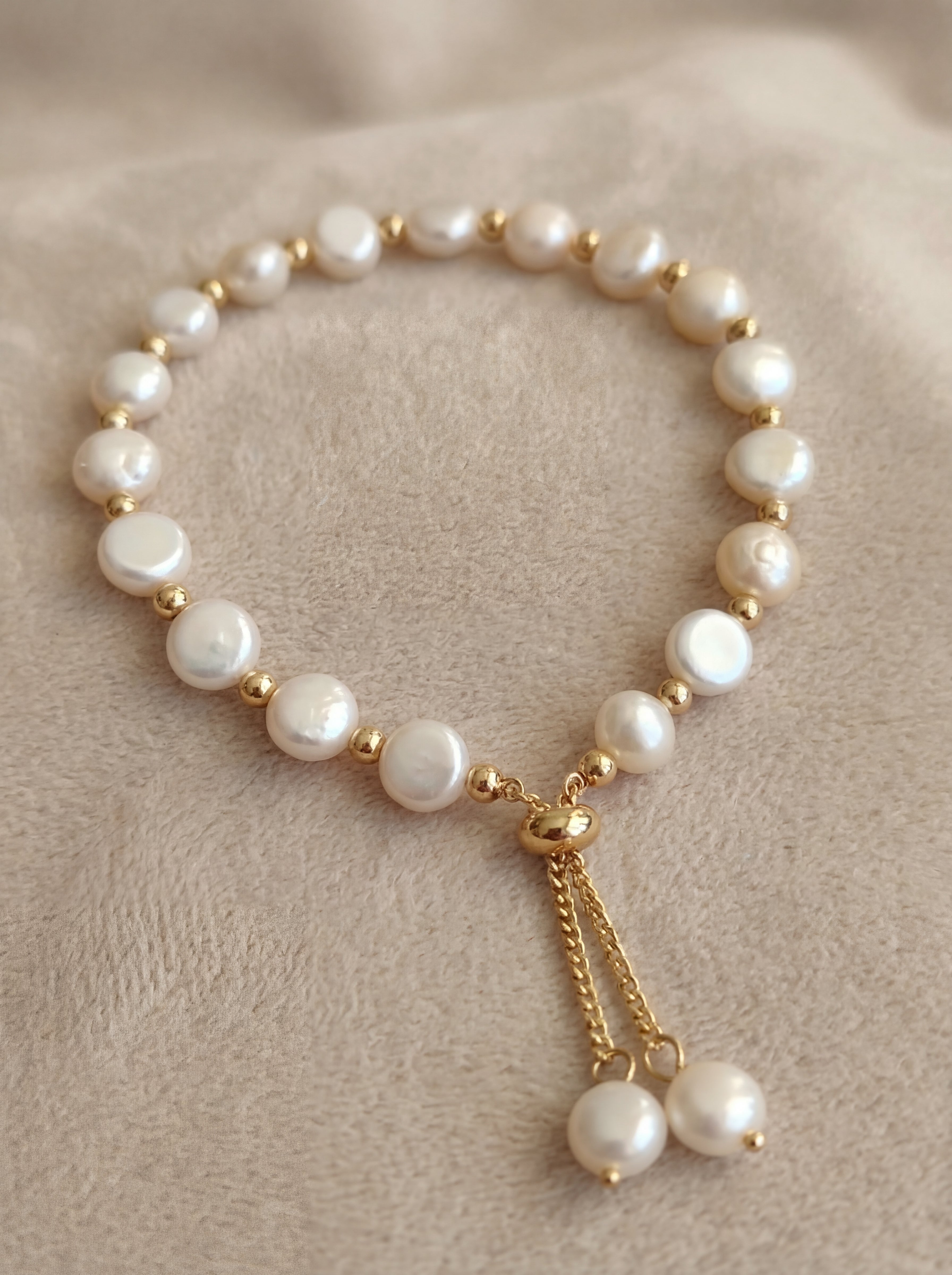 Pearl bracelet with gold accents on a beige fabric background