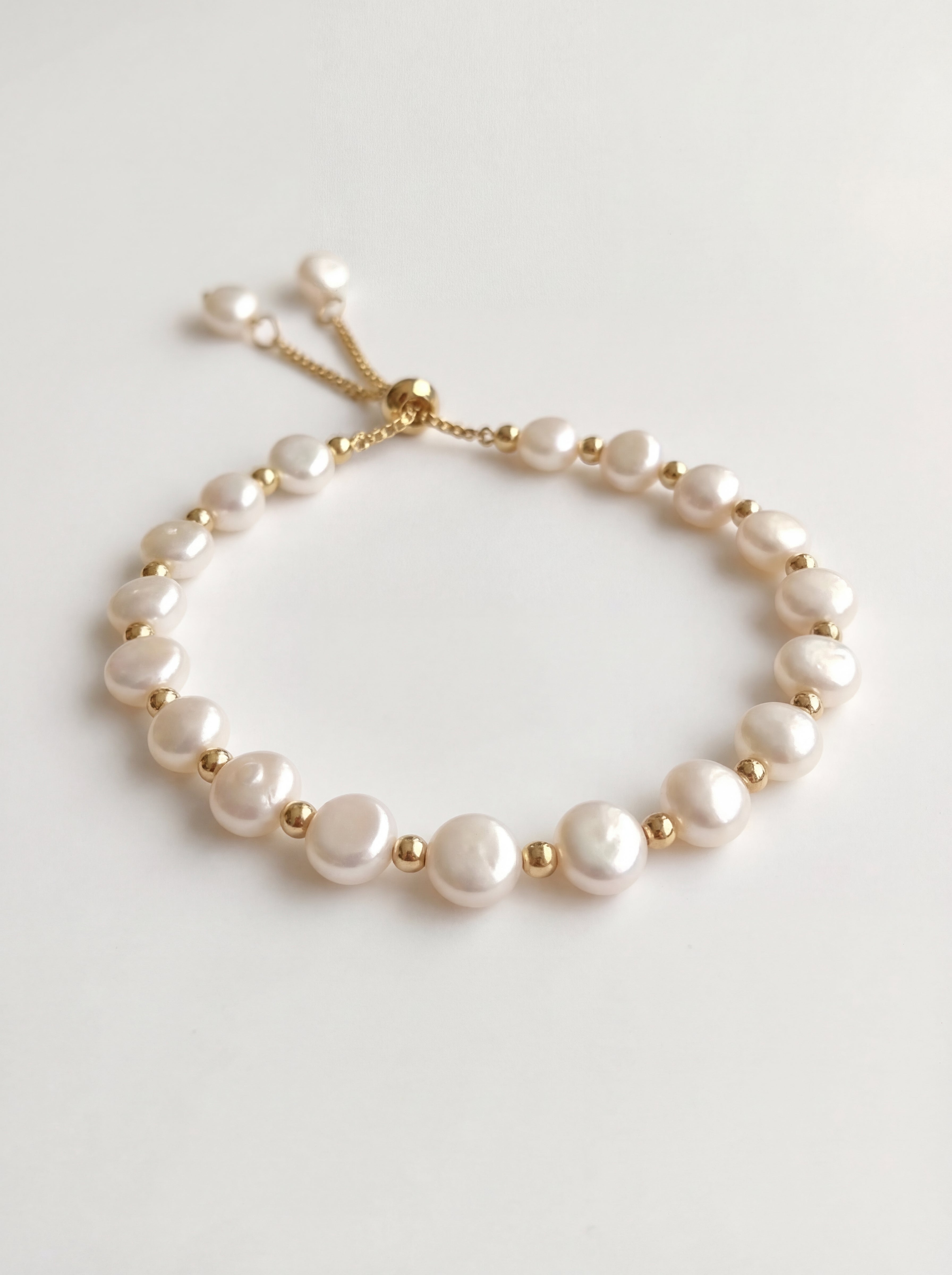 Pearl bracelet with gold accents on a light gray background