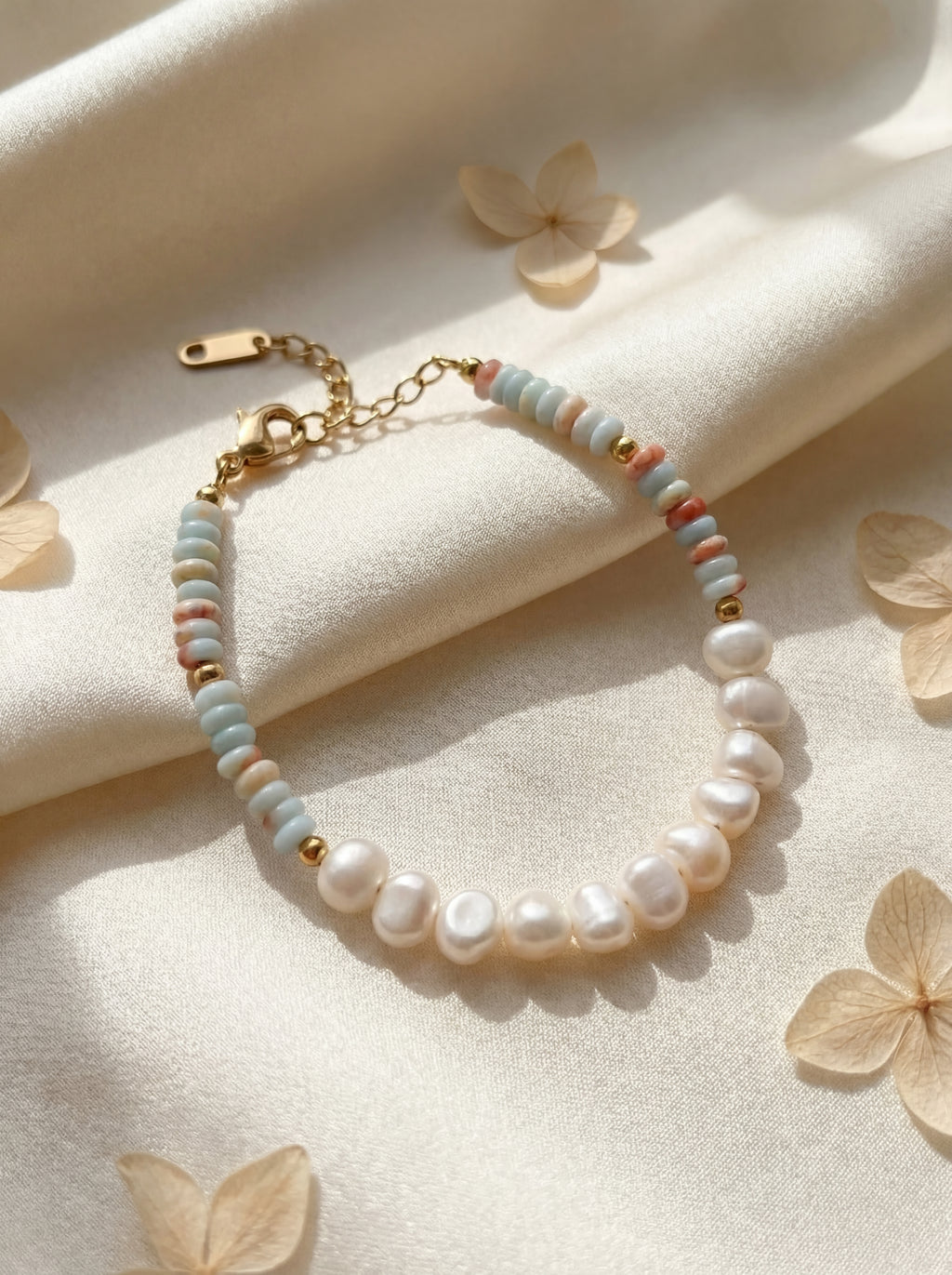 Beaded bracelet with gold chain on a beige fabric background