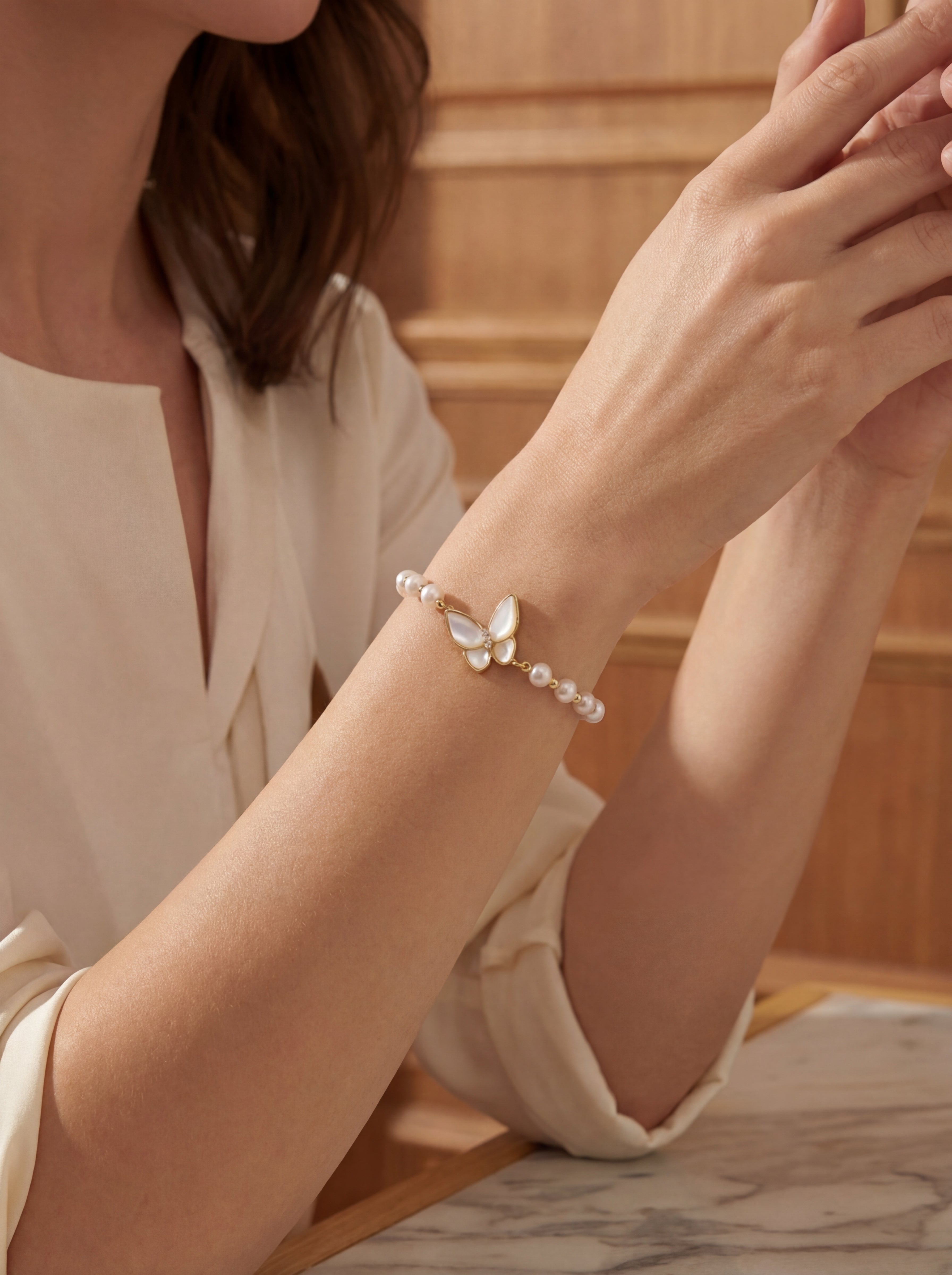 Woman wearing a bracelet with butterfly design on a neutral background