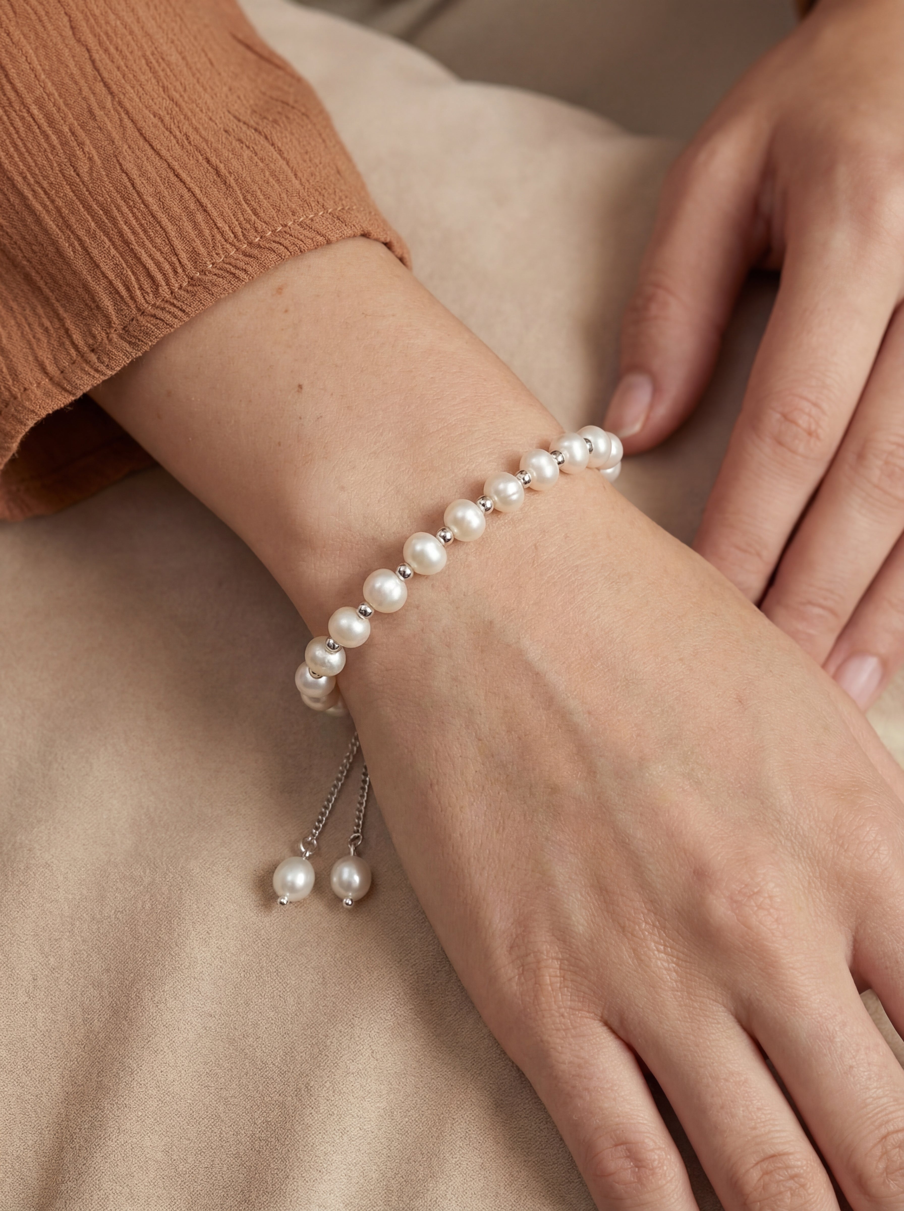 Pearl bracelet on a wrist with a neutral background
